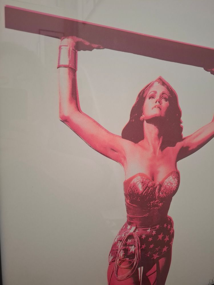 Lynda Carter as Wonder Woman holding up a steel beam 