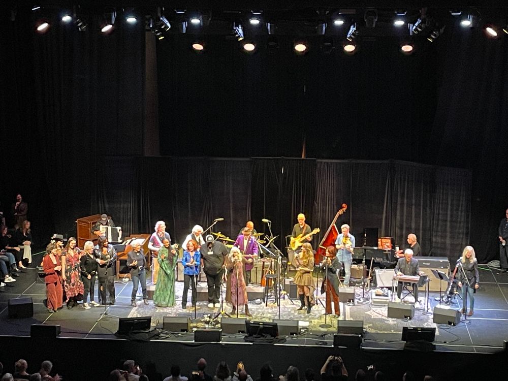Stage at the Masonic chock full of artists for the grand finale. The stage lights are bright and the band stands behind the lineup of singers clustered at standing microphones across the front 