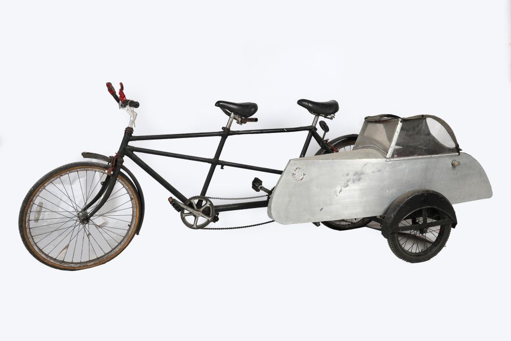 An old tandem bicycle with what seems to be a metal sidecar attached. Yes please!