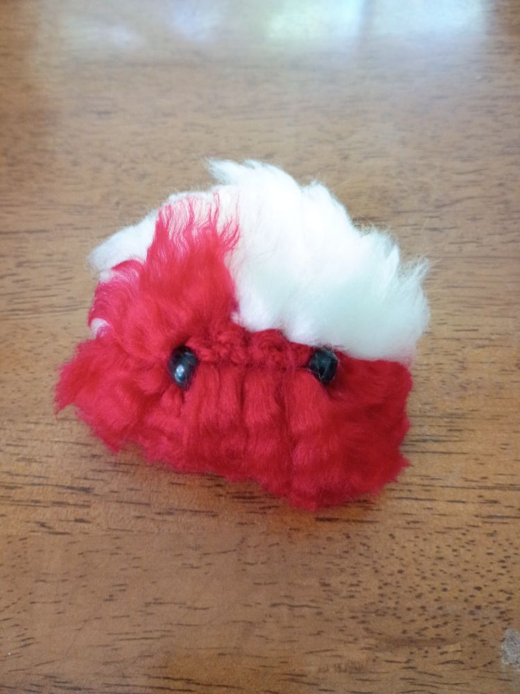 A white and red Worry Pet sits on a wooden table.