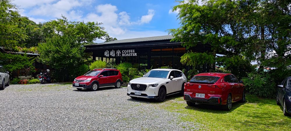 A free-standing coffee shop along the side of the road. Several cars are parked in front. 