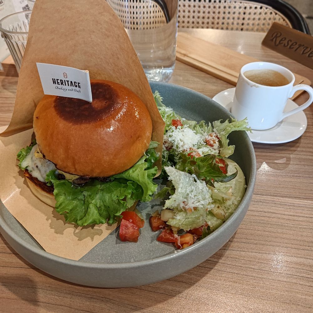 A burger and salad on a cafe table, with an espresso to the side. 