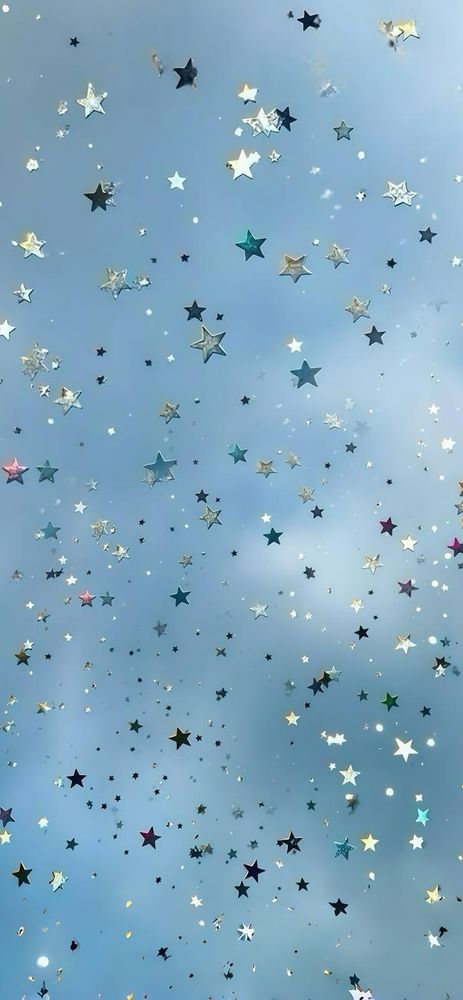 A dreamy image showing a sky-blue background scattered with shimmering star-shaped confetti in various sizes and colors. The stars are metallic and reflective, featuring hues of silver, gold, blue, green, pink, and purple. The confetti appears to be floating or falling, creating a magical, celestial effect reminiscent of stars twinkling in a gentle sky.