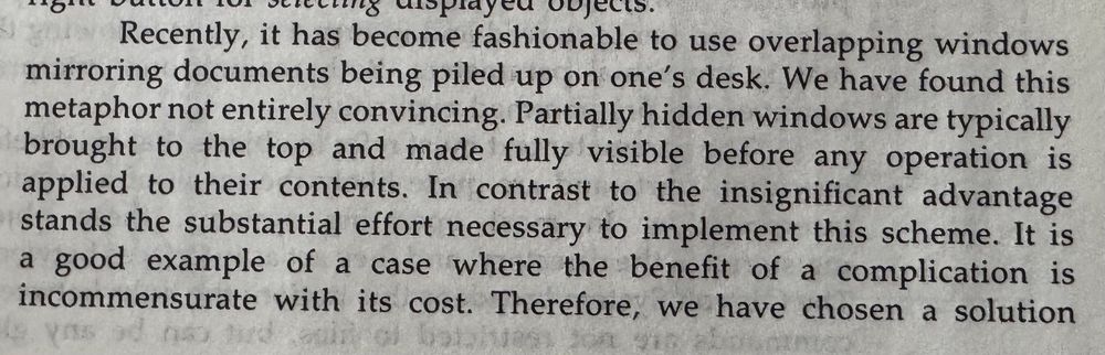 A paragraph of text discussing how overlapping windows mirroring stacked documents on a desk is not an ideal metaphor for computer interfaces. The text argues that partially hidden windows typically need to be brought to the top and made fully visible before use, and that the substantial implementation effort required outweighs the insignificant advantages of this design approach. It concludes by stating it's an example where a complication's benefit is incommensurate with its cost.​​​​​​​​​​​​​​​​