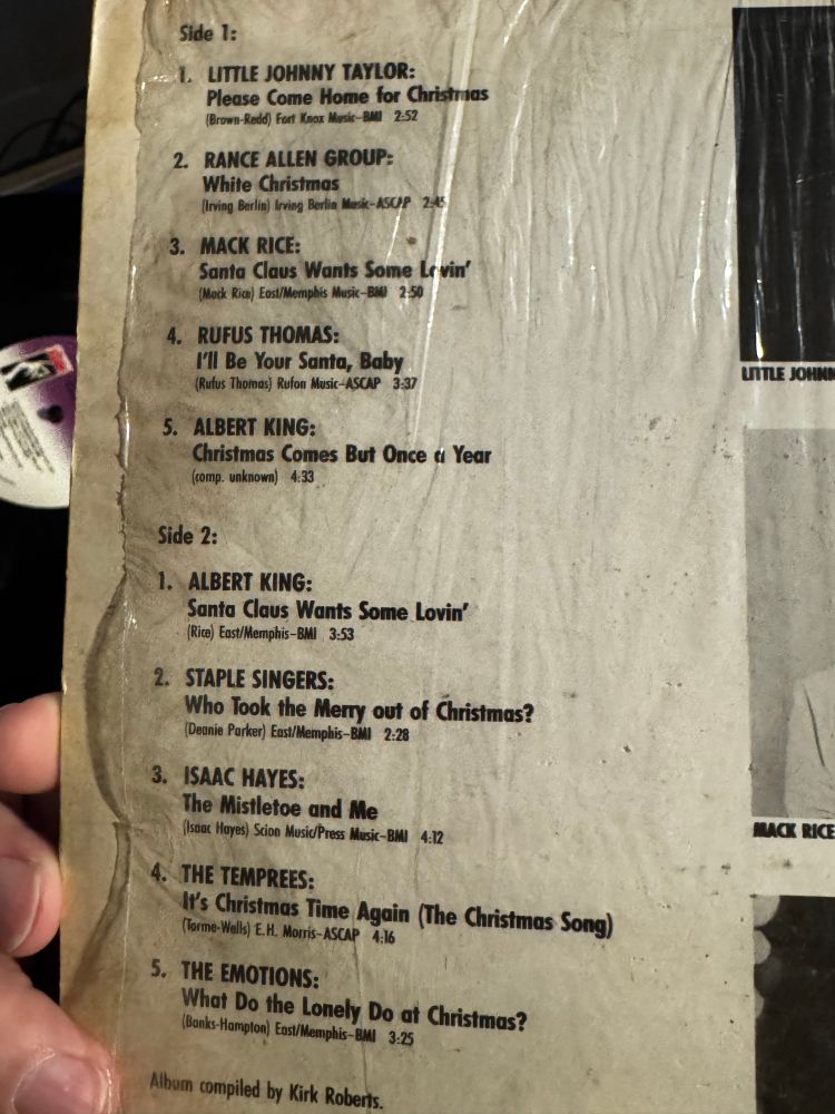 Close-up of the back cover of a vinyl record featuring a compilation of soul Christmas songs. The tracklist is visible, listing artists like Little Johnny Taylor, Rance Allen Group, Mack Rice, Rufus Thomas, Albert King, Staple Singers, Isaac Hayes, The Temprees, and The Emotions.