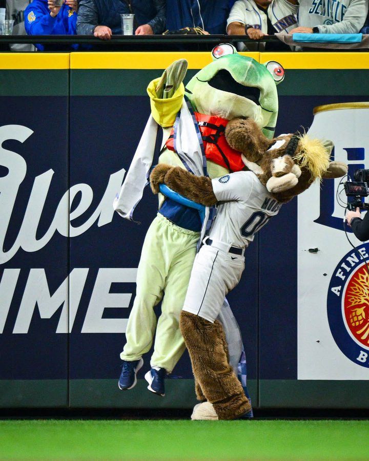 Humpy a racing salmon mascot for the Seattle Mariners being hugged and lifted up in celebration by the Mariners moose mascot 