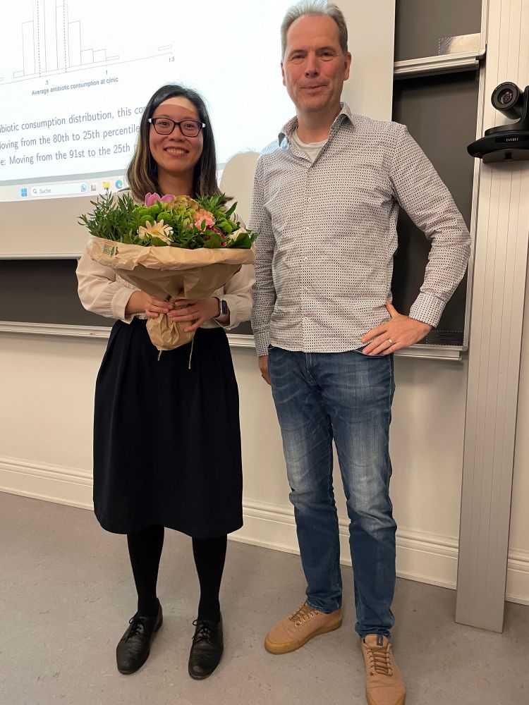 PhD candidate and advisor standing next to each other in front of a presentation slide