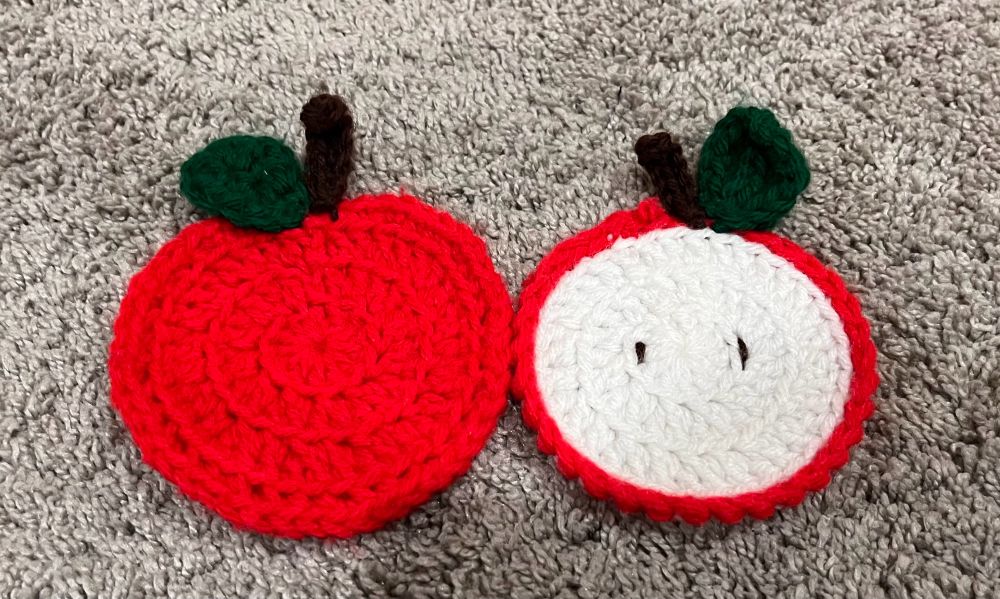 Crochet apple coasters on gray carpet