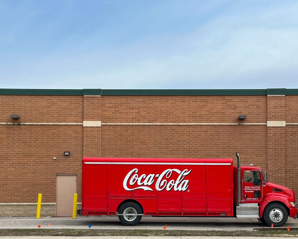 Bright red Coca-Cola truck against a brick building.