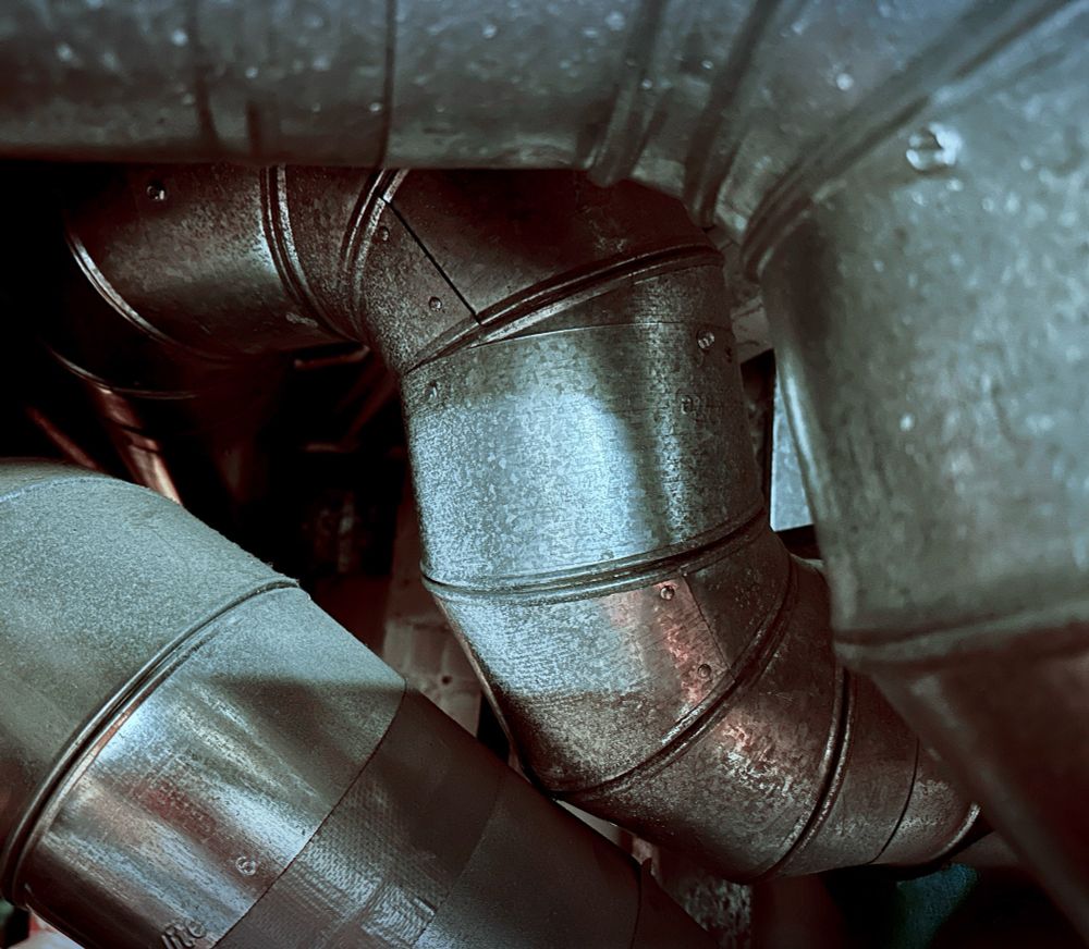 A closeup of furnace ductwork with several sheet metal elbows in the frame.