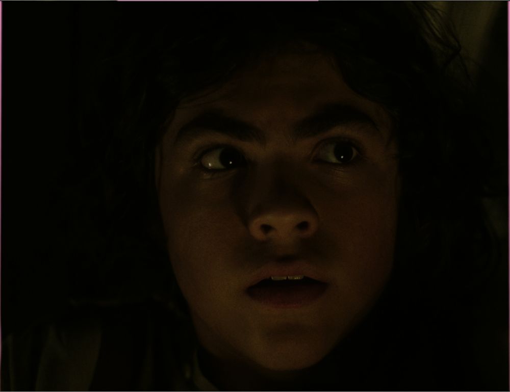 A photo of young boy Ed watching his parents fighting.  His eyes are huge and dark, and he looks scared.
