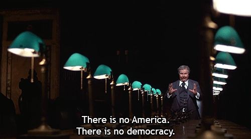 Ned Beatty at the head of the big conference table in Network. Caption reads: There is no America. There is no democracy. 