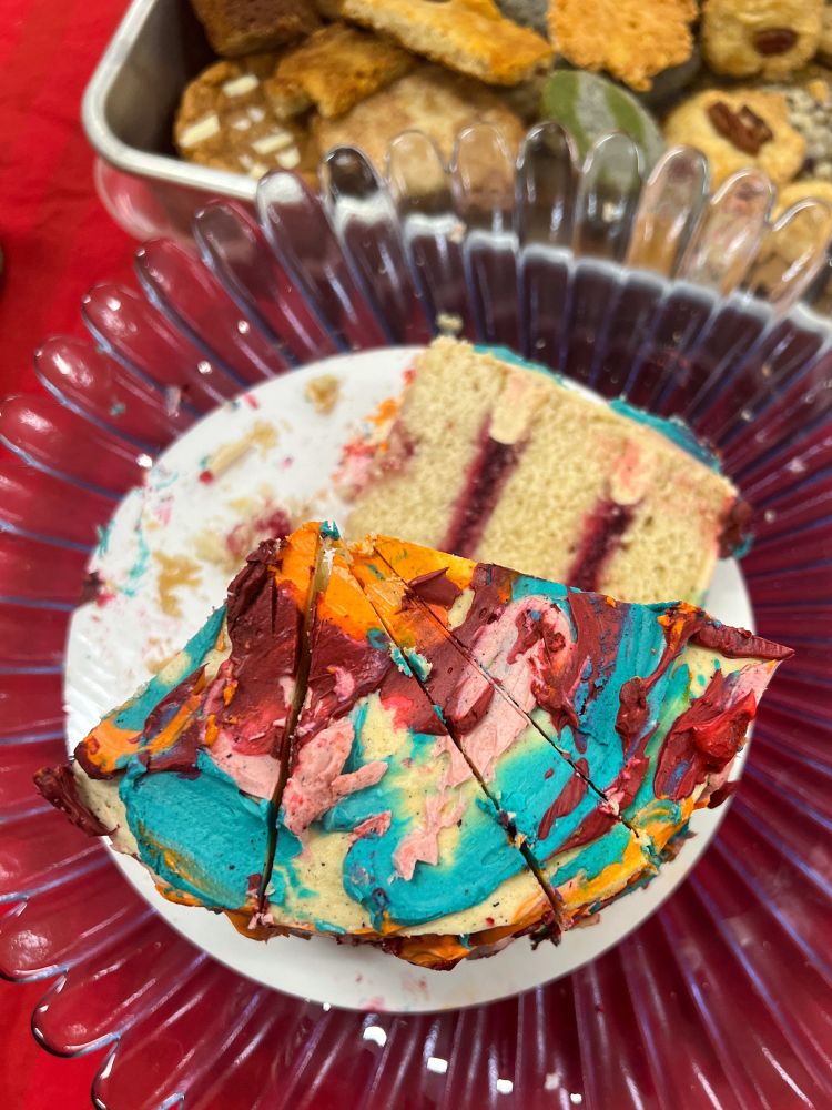 multicolor frosting swirled on unevenly sliced cake on a red background 