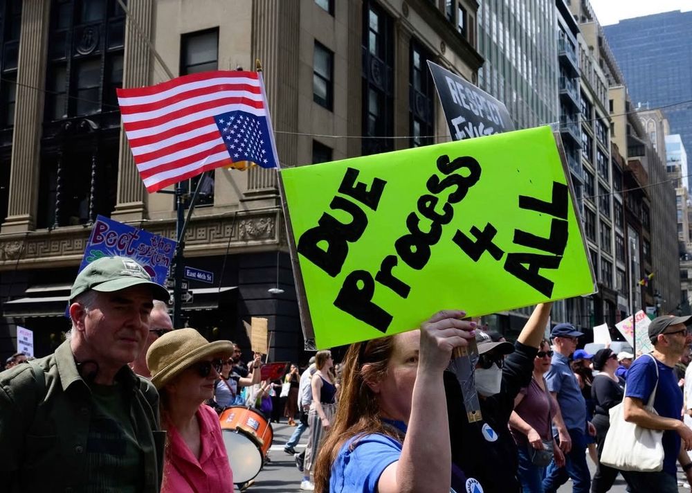 Protesters holding an upside down American flag and calling for due process for everyone 