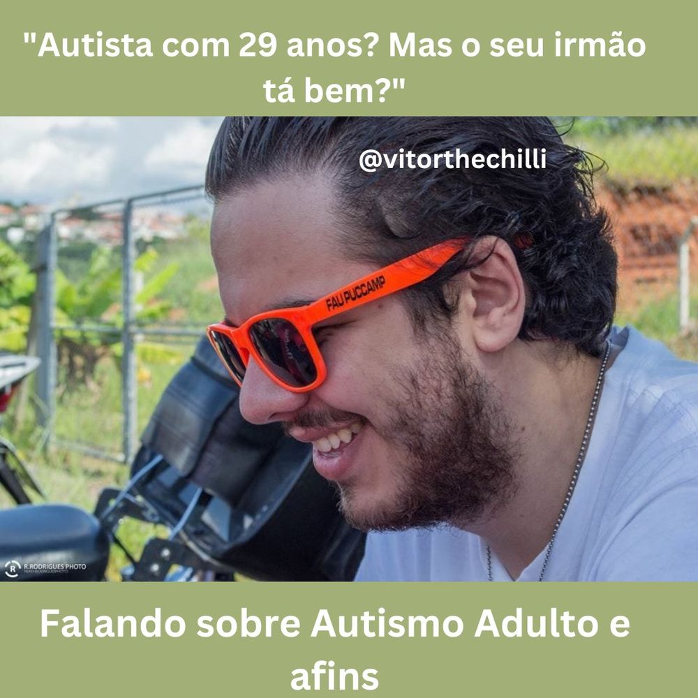 imagem de um homem com os cabelos curtos penteados para trás, com a barba por fazer
ele está sorrindo e veste uma camiseta branca, assim como está com um óculos escuro de hastes cor de laranja 