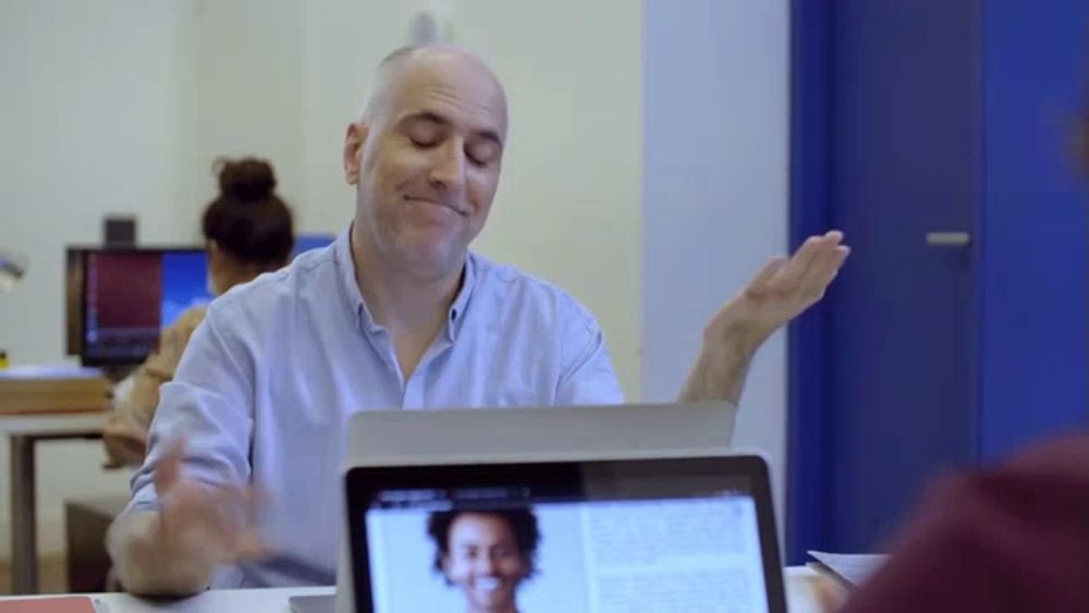 a man sitting in front of a laptop with a woman on it