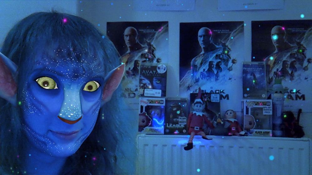 A picture of a beautiful Na'vi girl with her collection of human artifacts. Most, including three posters, one DVD, and two funko! pops are based on the film Black Adam, but she also has a PS3 copy of Avatar: the Game and several UMD films. For some reason two elves on the shelves have found their way into the shrine