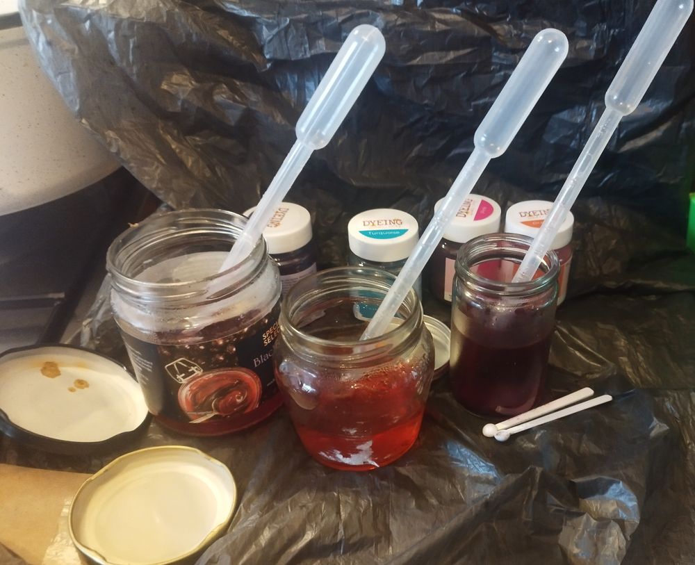 Three jars of made up dye solution in glass jars.