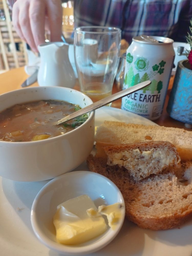 Bowl of soup, with bread and butter and a can of elderflower presse.  
