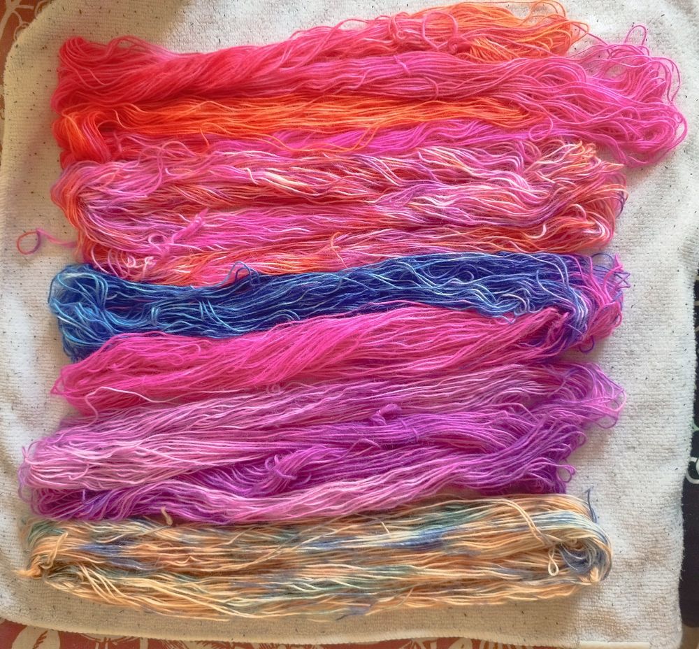 5x 20g skeins of sock weight Merino yarn which have been acid dyed in various shades of orange pink purple and blue.