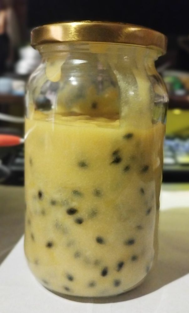 Jar filled with yellow mixture with black spots. It's Passion fruit curd.