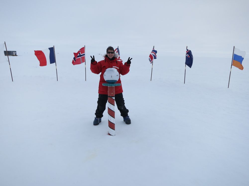 Woman standing behind ceremonial South Pole marker