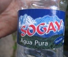 A bottle of water, the label is typical of bottled water, a blue sky, glacial mountain and a forest but in the foreground in massive red text is the brand 'sogay'