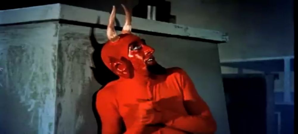The Devil, dressed in the manner described in the main post, hides behind a chimney in a scene from "Santa Claus Vs. The Devil (1959).