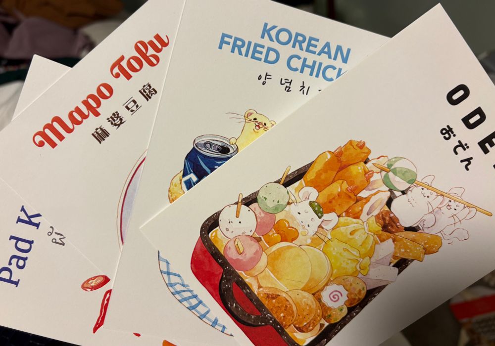 A spread of for recipe cards. Left to right: pad kee mao, mapo tofu, Korean fried chicken, oden. They all have cute creatures in a picture of food, which would be gross in real life, but is cute for an image.