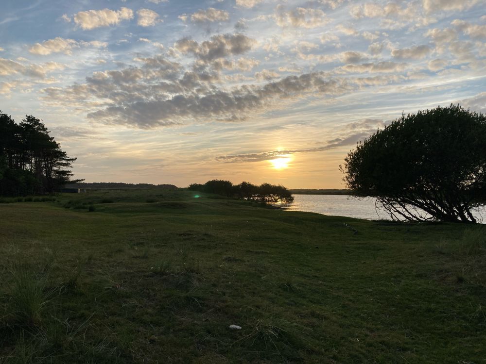 Sunset through the clouds with water and trees