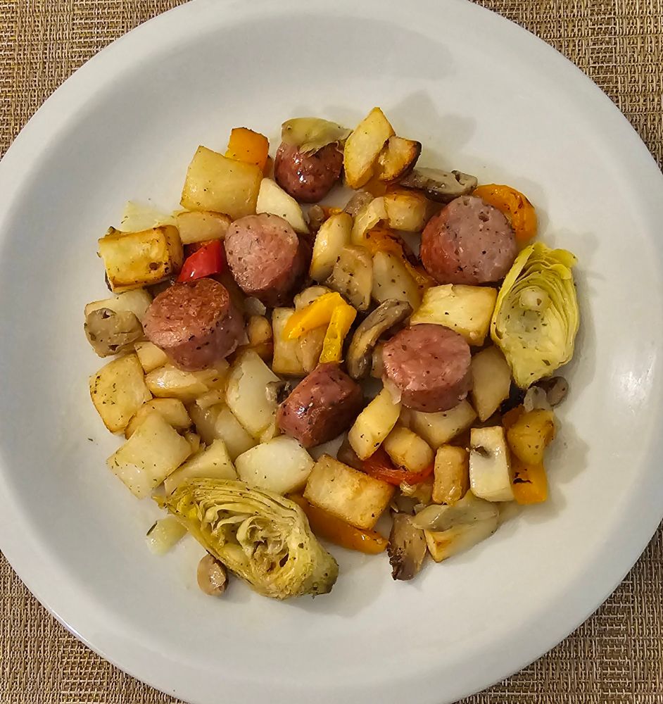 Picture of baked and broiled gruyere and roasted garlic sausage, diced potatoes, bell peppers, onion, mushrooms and artichoke hearts tossed in olive oil on a white ceramic plate. It was very yummy 😋