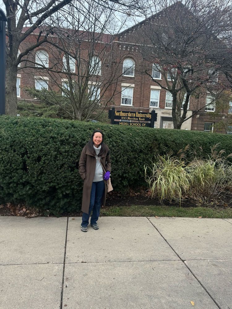 A female stands in front of a Medill School of Journalism sign 