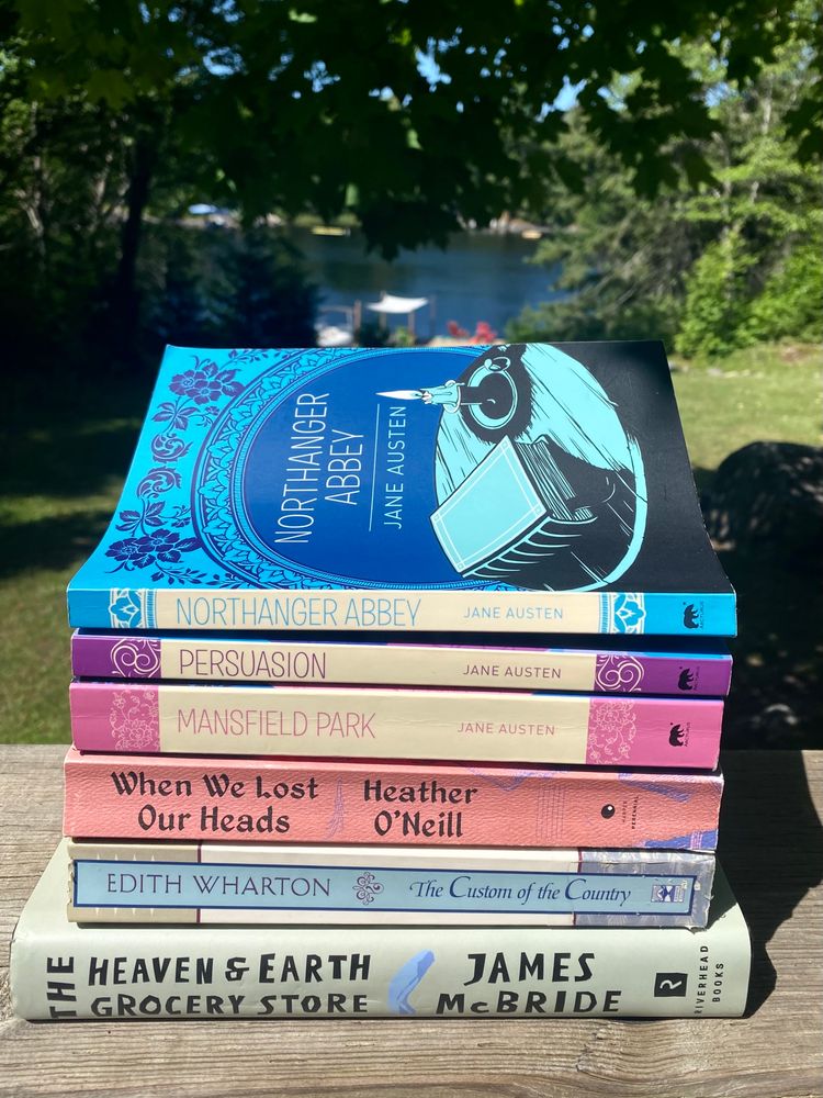 A stack of books: 
Northanger Abbey, Persuasion, and Mansfield Park by Jane Austen
When We Lost Our Heads by Heather O’Neill
The Custom of the Country by Edith Wharton 
The Heaven and Earth Grocery Store by James McBride 
