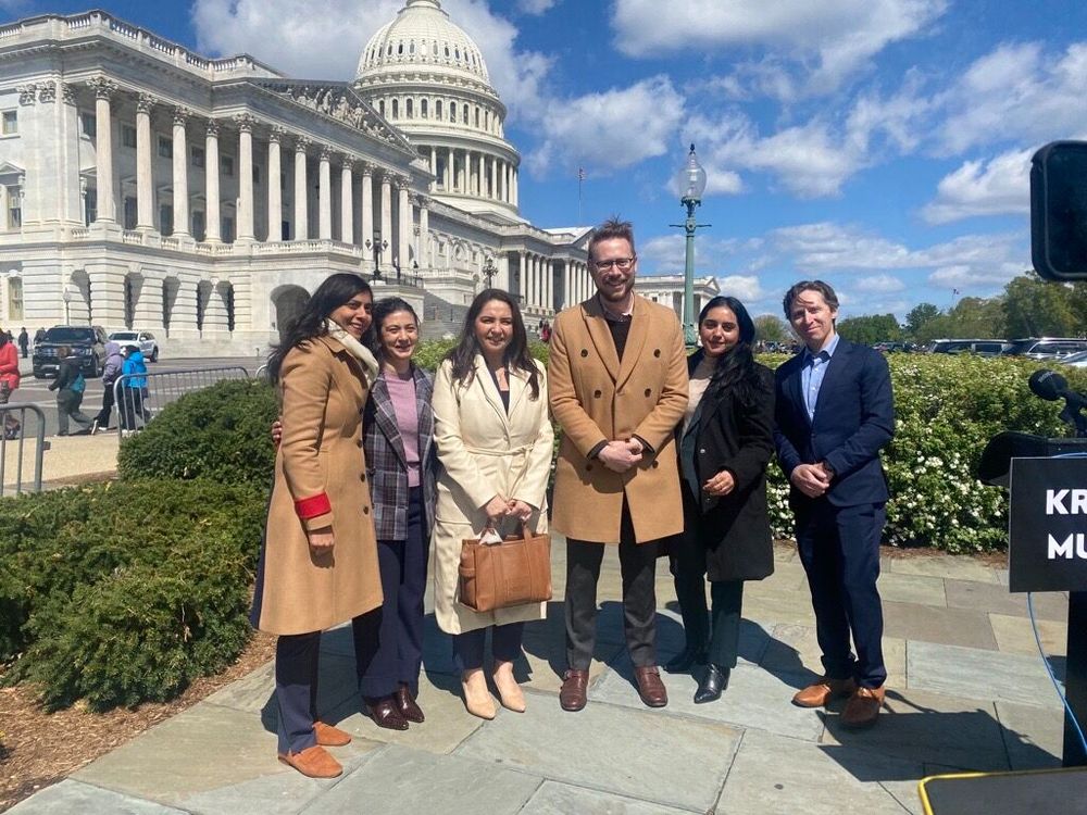 Jesse Franzblau poses with a group of U.S. elected officials and immigration advocates for a photo in front of the United States Capitol building.
