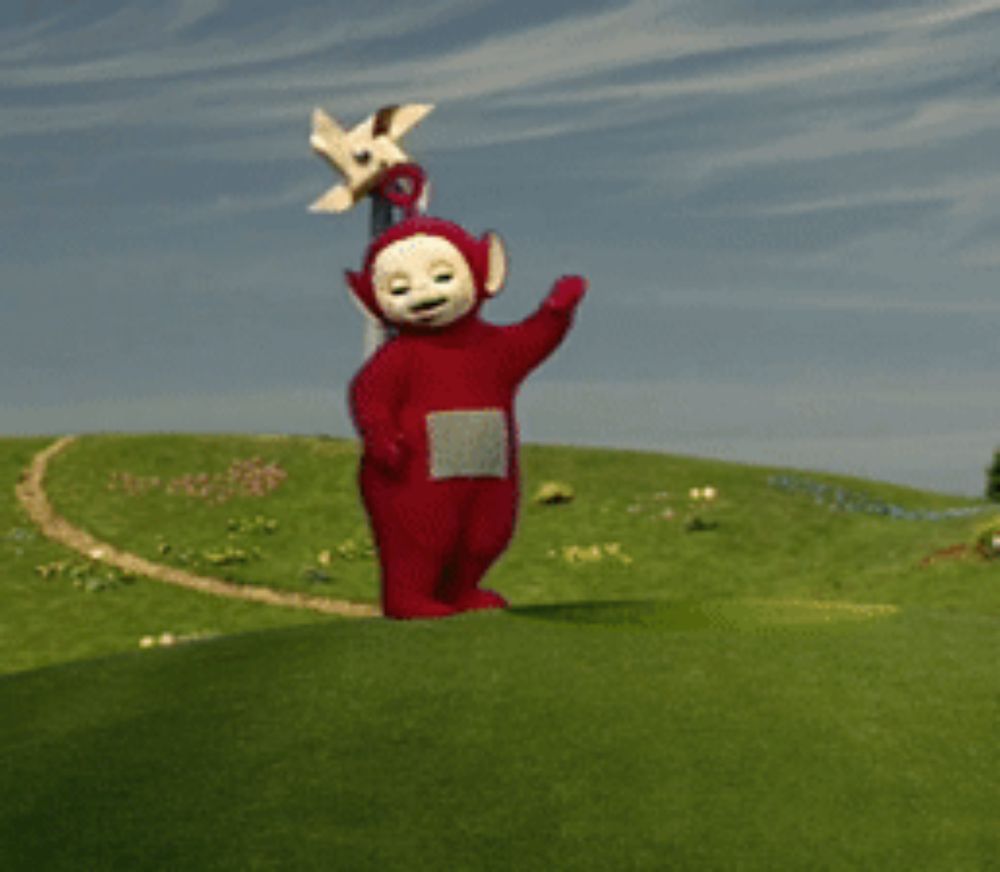 a red teletubbies character is standing on a grassy hill