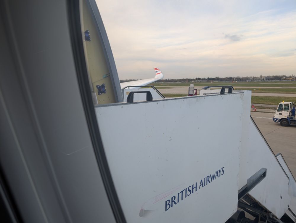 Long distance view of the wing of a British Airways aircraft looking out over the curved wingtip that shows the BA logo