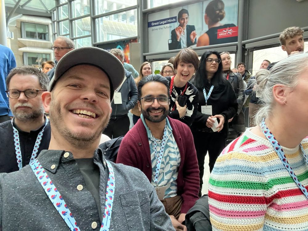 Selfie of Brendan, Prateek and Lara in the audience at UK GovCamp 2025 at MoJ Building, Petit France, London
