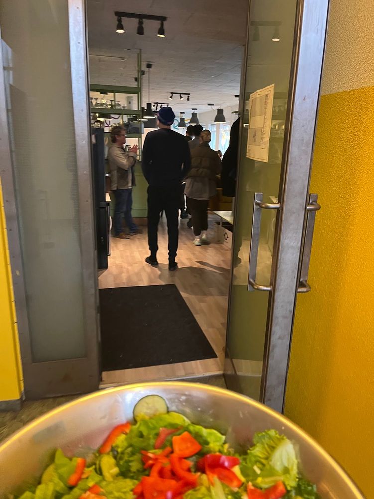 Perspective of someone carrying a big bowl of salad entering a large room full of people