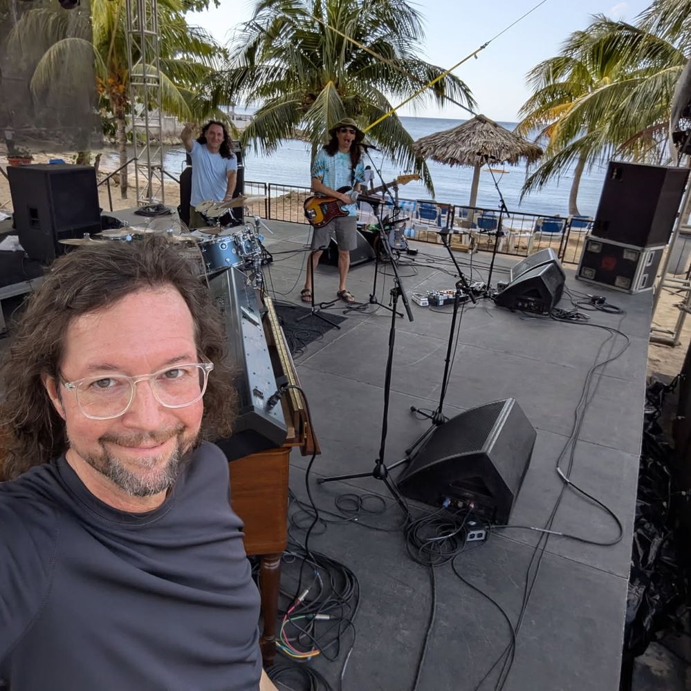 John Kadlecik, JP McLean, and Jeremy Hoeing setting up for a performance on a beachside stage in Jamaica.