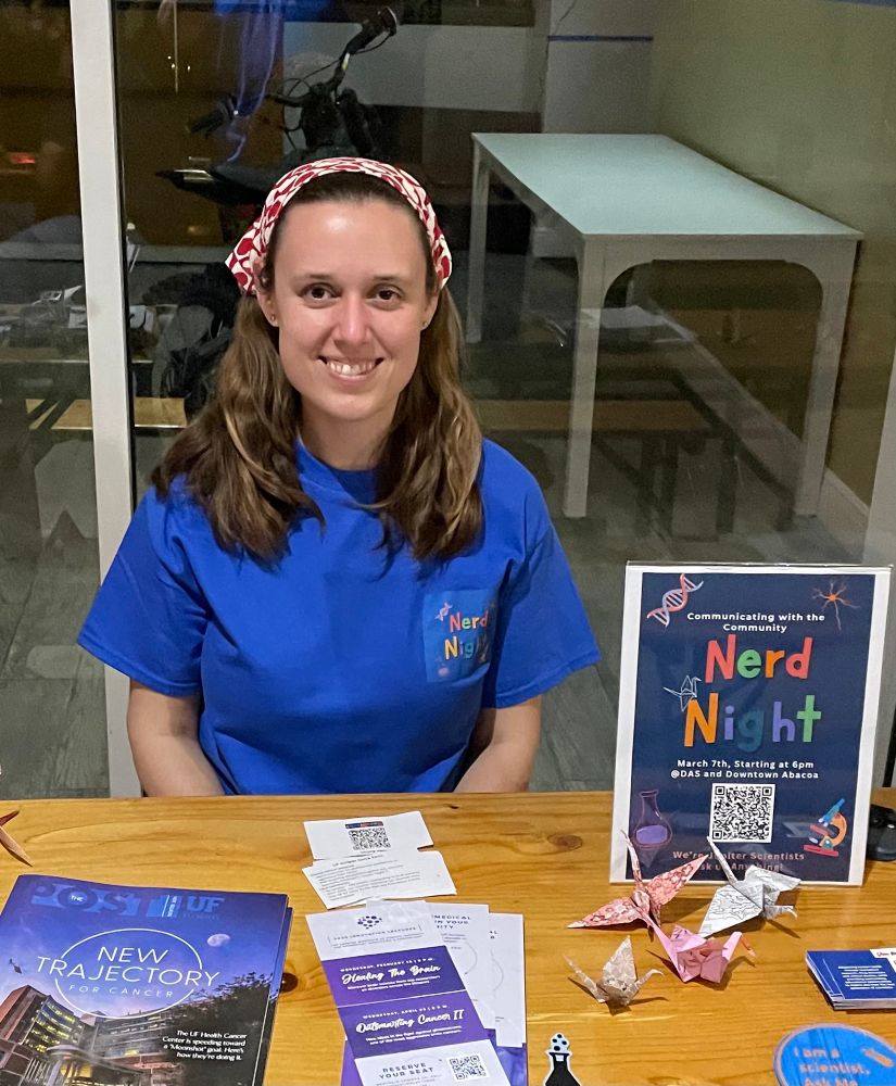 Scientist with a sign that says nerd night and flyers on a table 