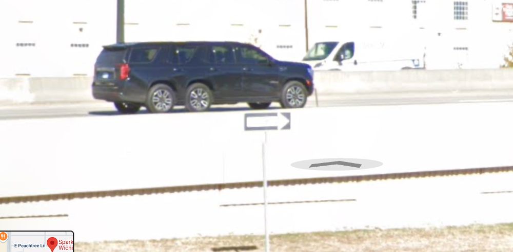 Picture of a full size dark blue SUV...maybe a Suburban (?) going down the highway. This is a screen grab from Ggl maps and the SUV has six wheels and six doors. Whoops.