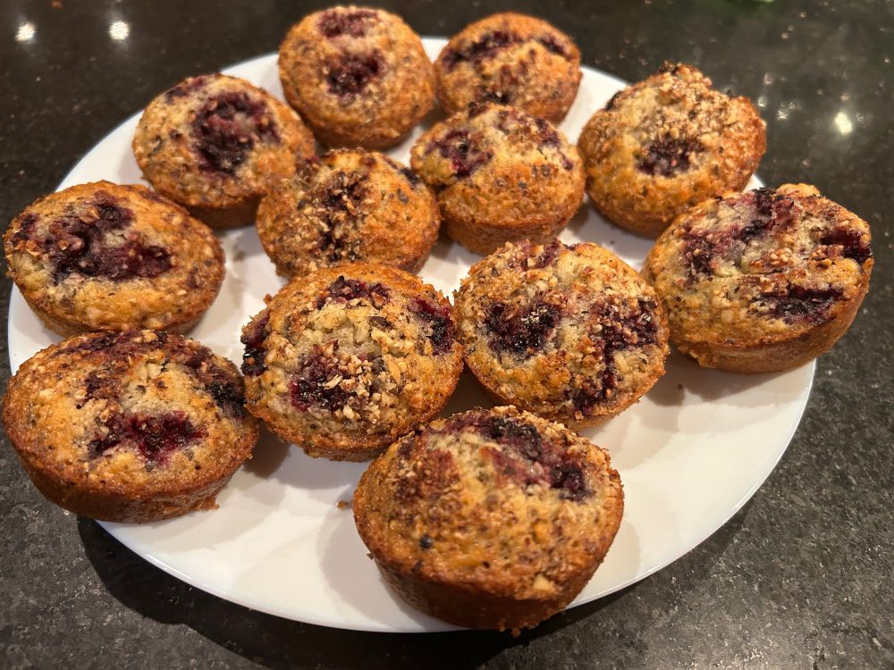12 blackberry and hazelnut friands on a white plate.