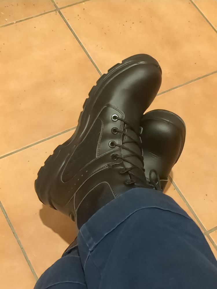 a pair of black boots on my feet. they have a solid heel and also their design makes them look a little bit like snowboarding boots