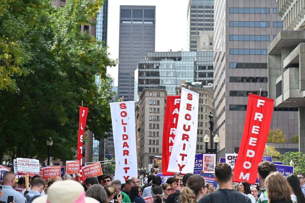 An image of red and white signs at the 2025 Boston Labor Day parade that read words like 