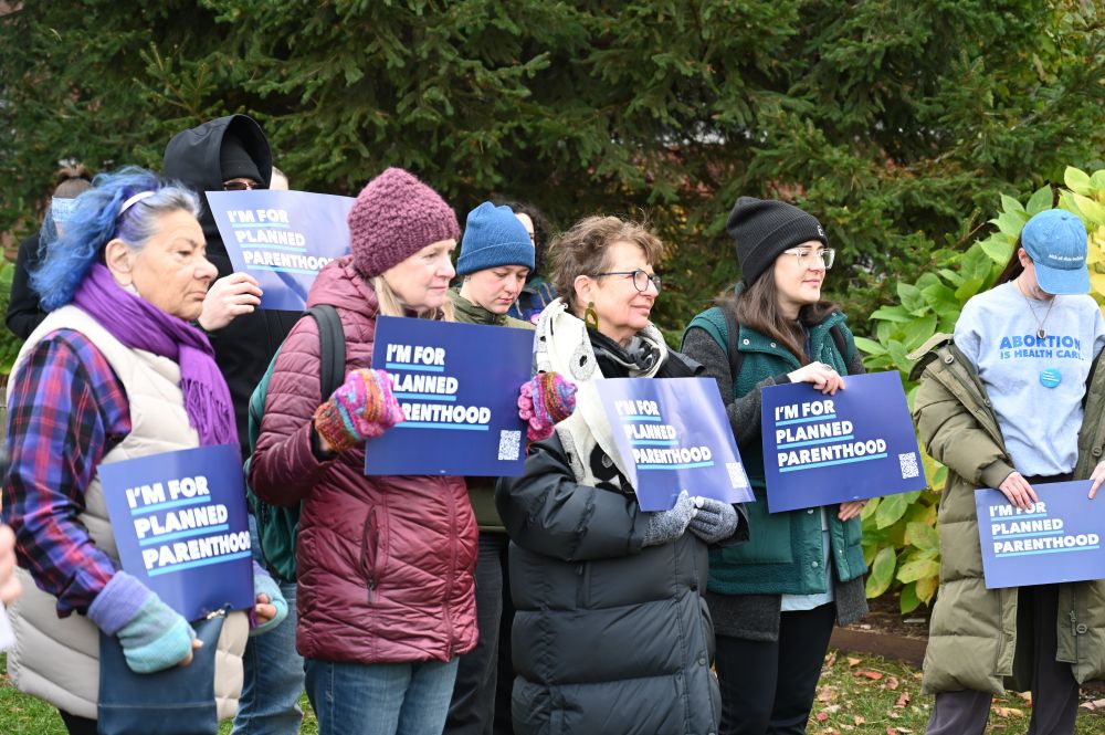 A photo of attendees at the Planned Parenthood Rally holding up blue signs that say "I'm for Planned Parenthood"