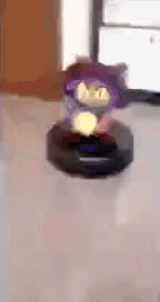 a robotic vacuum cleaner is cleaning a room with a purple object in the background .