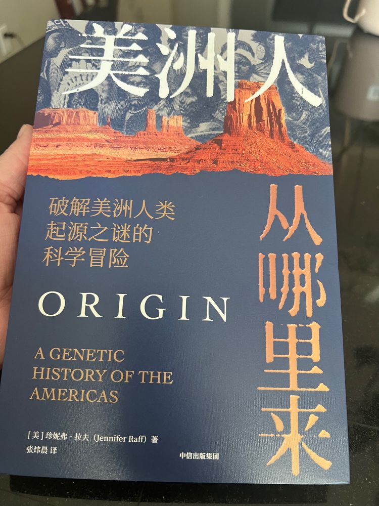 A hand holding a book titled “Origin: A genetic history of the Americas” translated into simplified Chinese.