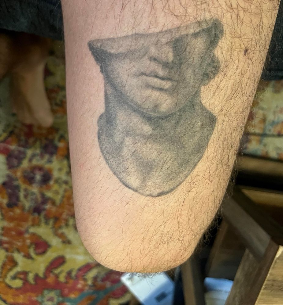 The full tattoo is a broken bust sculpture and the “dick” is made up of the sculpture’s neck 