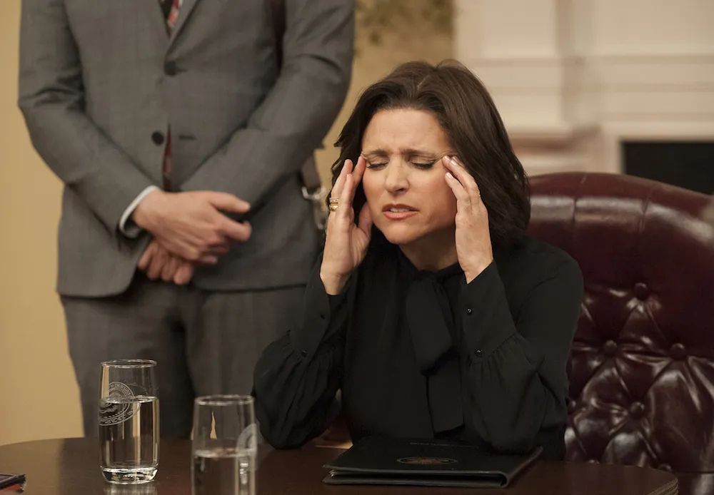 Gary standing behind Selina Meyer who’s touching her temples 