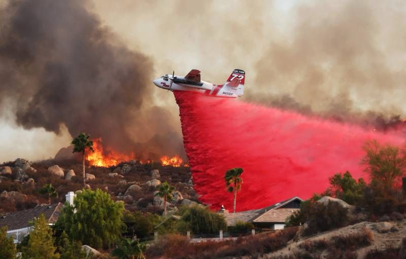 A plane dropping bright pink fire retardant over LA homes